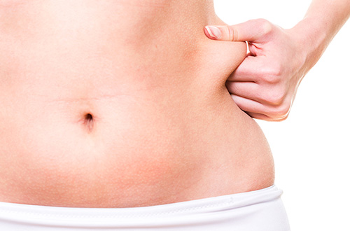 Vrouw houdt love handle vast ter illustratie van cryolipolyse behandeling